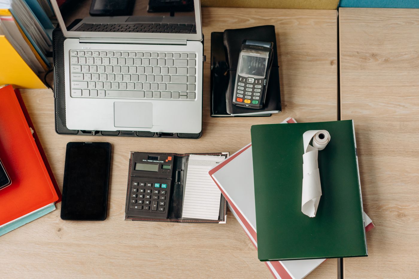 Business desk with a laptop, calculator, card terminal and financial documents